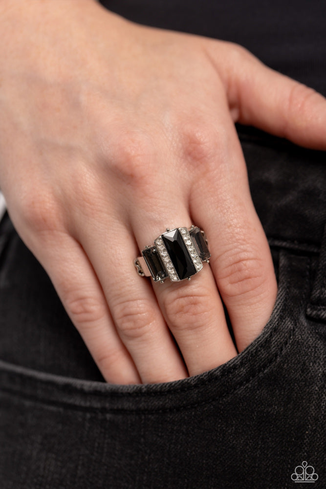A Glitzy Verdict - Black and Silver Ring - Paparazzi Accessories - Bordered by two rows of dainty white rhinestones, an emerald cut black rhinestone adorns the center of a band dotted with a pair of smoky emerald cut rhinestones, resulting into a jaw-dropping dazzle across the finger. Features a stretchy band for a flexible fit. Sold as one individual ring.
