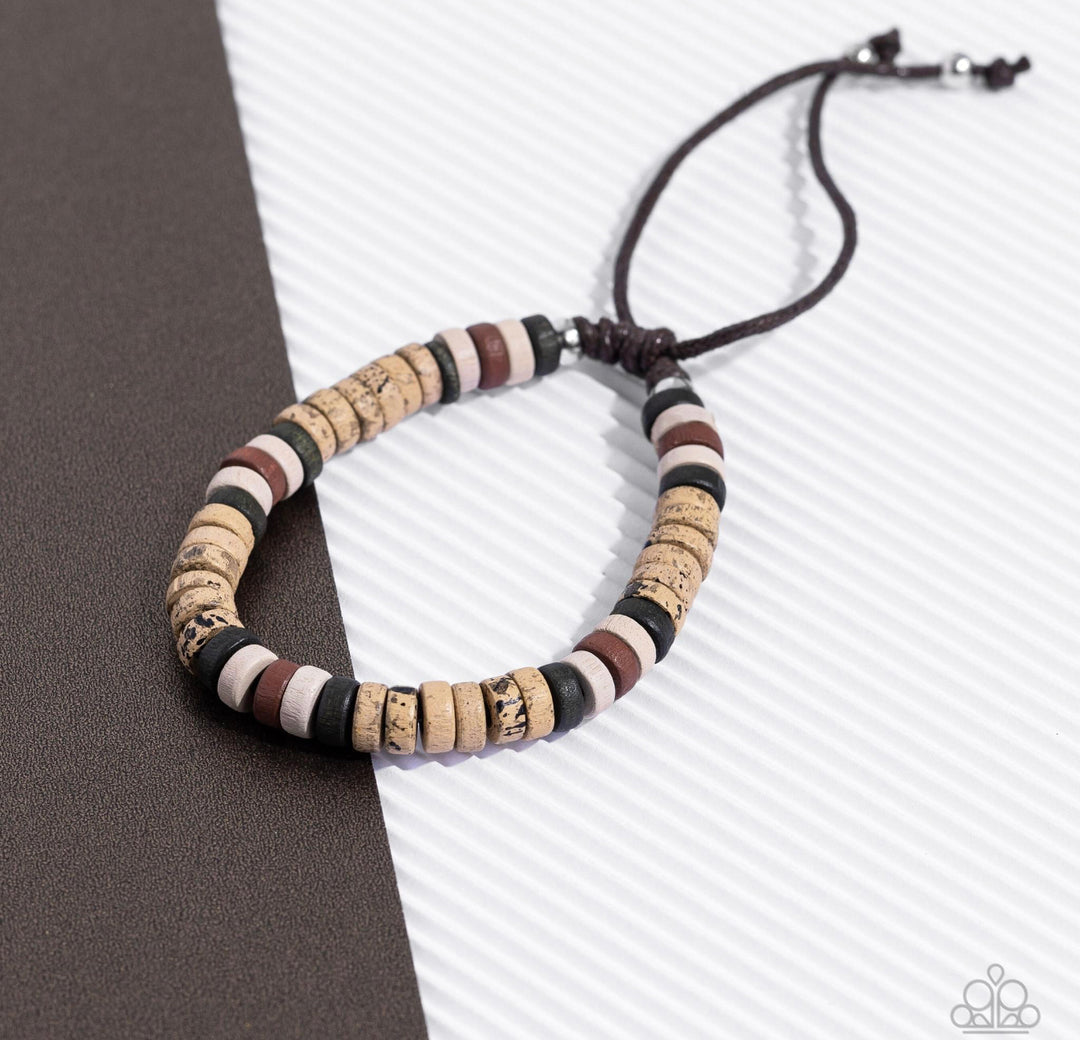 Wild Wanderer - Brown Urban Bracelet - Paparazzi Accessories - An earthy collection of green, white, brown, and speckled wooden discs are threaded along a brown cord around the wrist for an adventurous pop of color. Features an adjustable sliding knot closure. Sold as one individual bracelet.