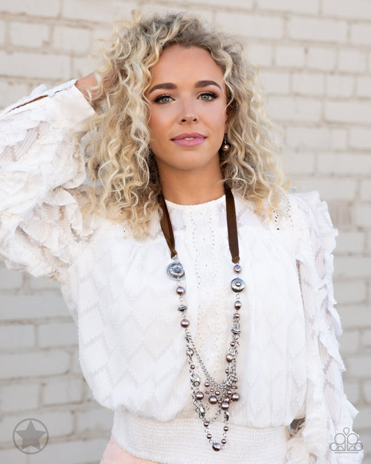 All The Trimmings - Brown and Silver Necklace - Paparazzi Accessories - A silky brown ribbon replaces a traditional chain to give an elegant look. Pearly brown beads and funky silver pieces intermix with varying lengths of silver chains to give a fresh take on a Victorian-inspired fashion necklace.