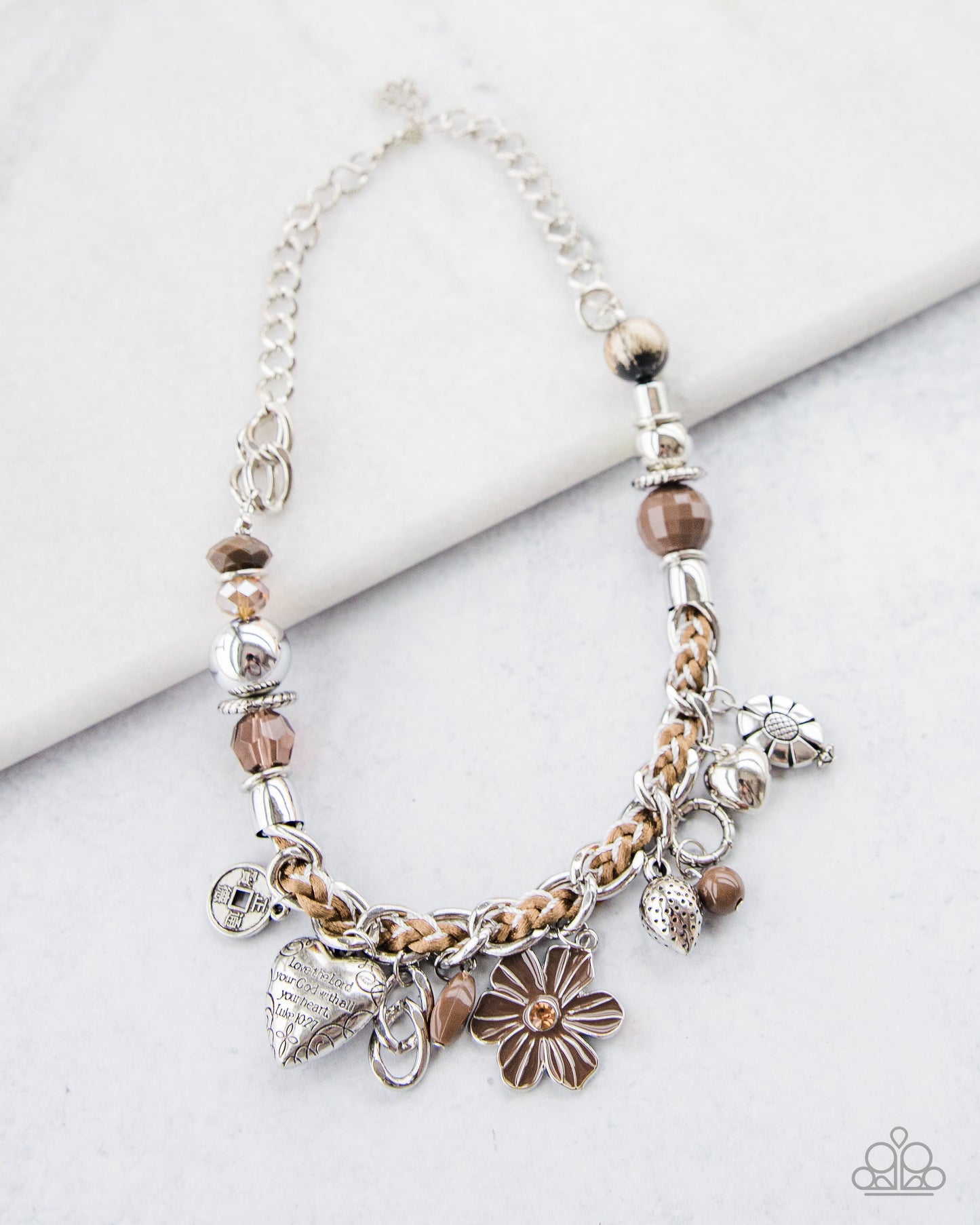 Charmed, I Am Sure - Brown and Silver Necklace - Paparazzi Accessories - Brown and ivory cording is braided through a chunky silver chain. A unique variety of charms decorate the piece including a delicate flower and a heart inscribed with the phrase "With All My Heart" on one side and a short bible verse on the other that reads, "Love the Lord thy God with all your heart. Luke 10:27" Features an adjustable clasp closure.