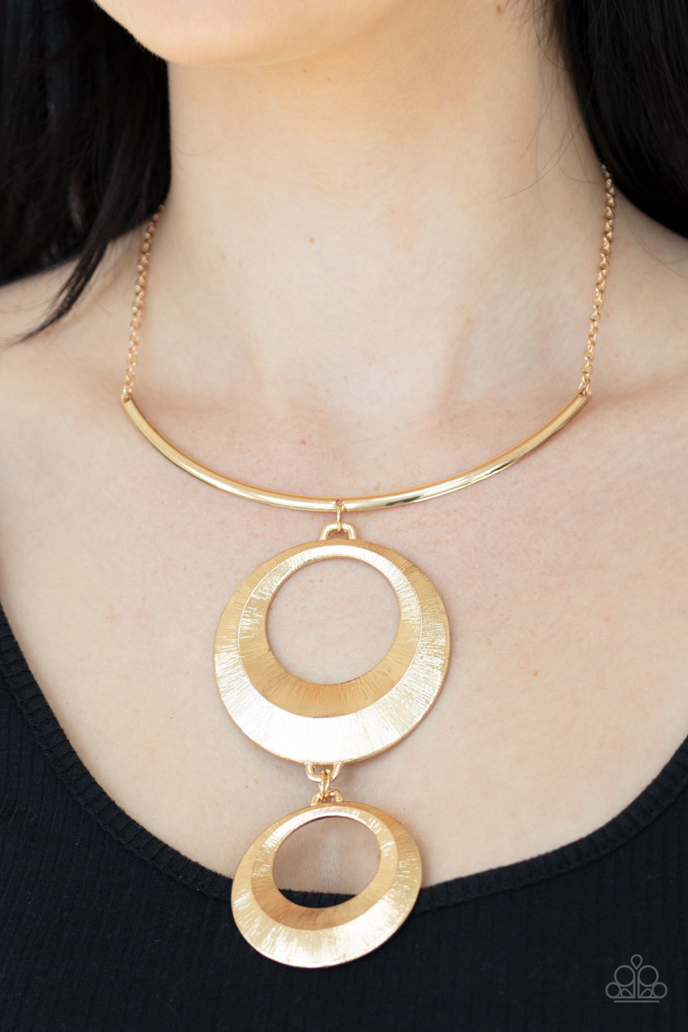 Egyptian Eclipse - Gold Fashion Statement Necklace - Paparazzi Accessories - Featuring a blinding scratch finish, two beveled gold circular frames swing from the bottom of a bowing gold rod, creating an edgy stacked pendant down the chest. Features an adjustable clasp closure. Sold as one individual fashion necklace.