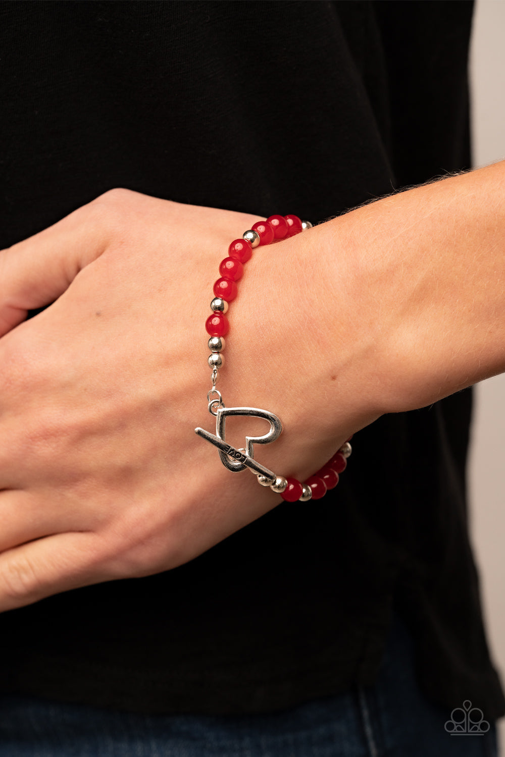 Following My Heart - Red Bead and Silver Bracelet - Paparazzi Accessories - Shiny silver heart frame interlocks with a toggle closure at the center of a shiny silver and glassy red beaded bracelet. The silver toggle is stamped in the word, "love," for a romantic finish. Features a toggle closure.
