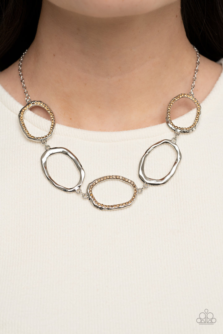 Gritty Go-Getter - Brown and Silver Necklace - Paparazzi Accessories - A row of dazzling light topaz rhinestones makes its way around a delicately hammered imperfect circular frame. The airy frames alternately link end to end with similar shiny silver frames creating a glitzy fashion across the collar.