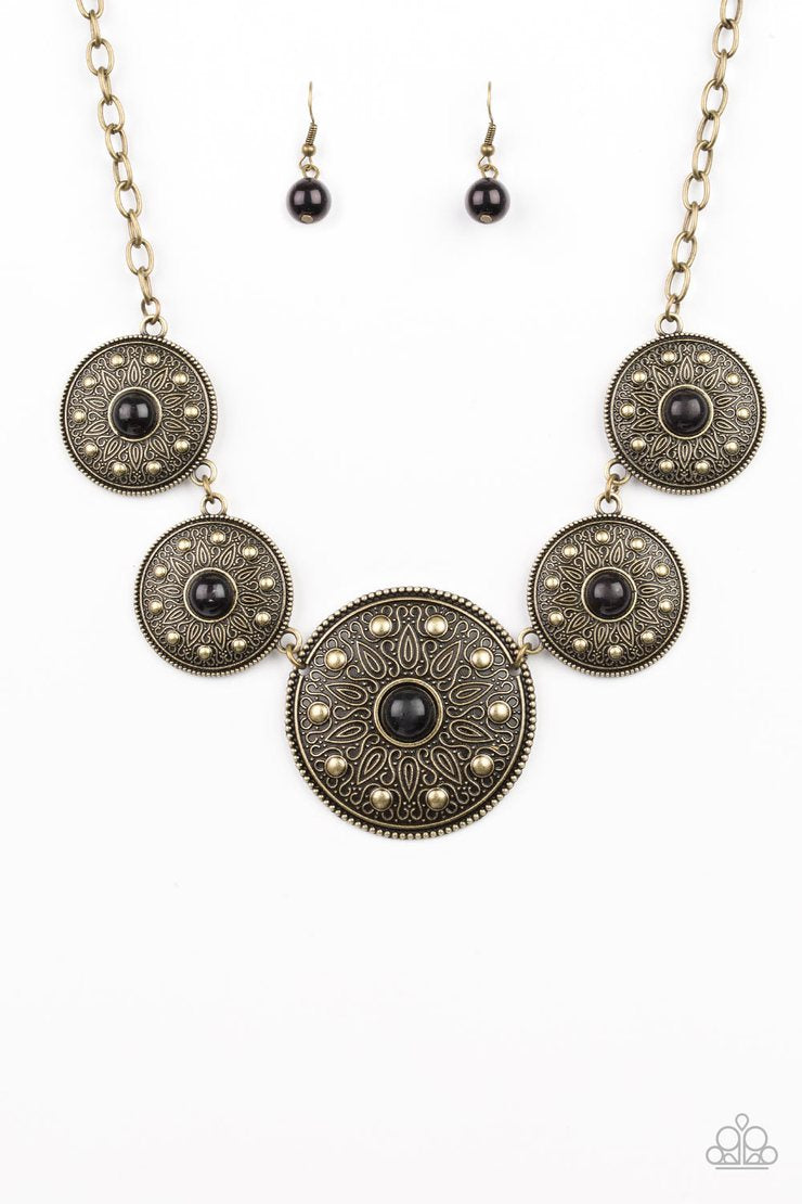 Hey, SOL Sister - Black and Brass Necklace - Paparazzi Accessories - Gradually increasing in size near the center, round brass frames radiating with sunburst patterns link below the collar. Infused with shiny brass studs, the tribal inspired frames are dotted with black beaded centers for a colorful finish. Features an adjustable clasp closure fashion necklace.