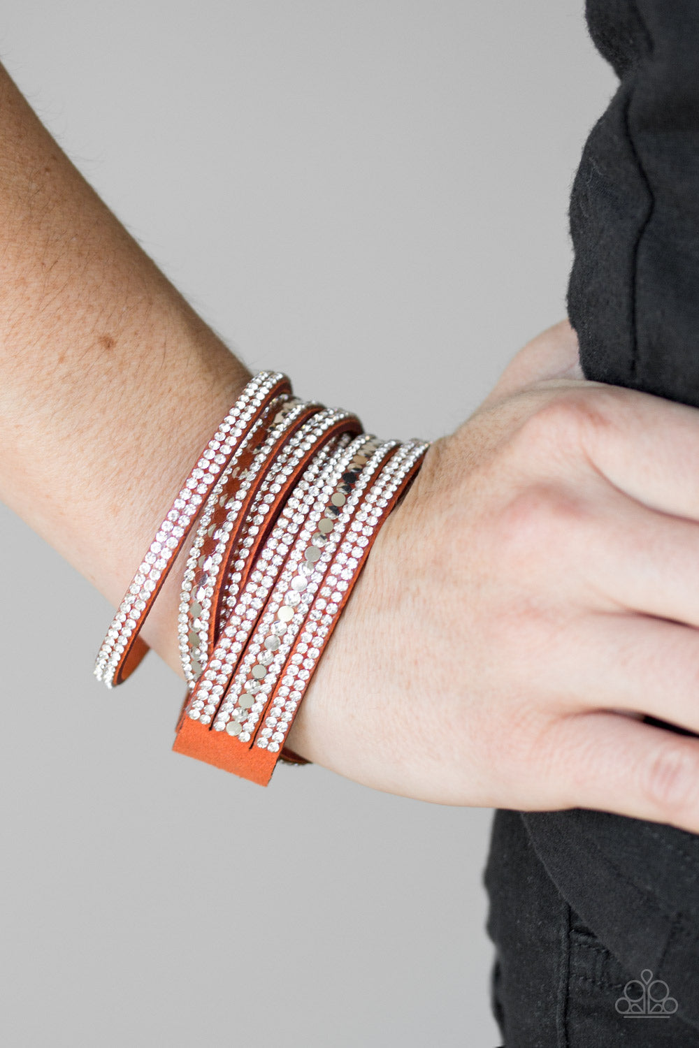 Rock Star Attitude - Orange Suede Wrap - Snap Closure Bracelet - Paparazzi Accessories - Encrusted in rows of glassy white rhinestones and flat silver studs, three strands of Burnt Orange suede wrap around the wrist for a sassy look. The elongated band allows for a trendy double wrap around the wrist. Features an adjustable snap closure. Sold as one individual bracelet.