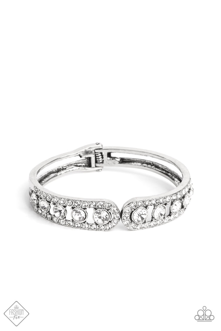 Spellbinding Splendor - White and Silver Bracelet - Paparazzi Accessories - Dazzling white rhinestones fall in line between two thick bands of silver, as they wrap around the wrist in a glitzy display. The rhinestones gradually increase in size as they lead towards the center, matching the flared ends of their silver encasement. Features a hinged closure. Sold as one individual bracelet.