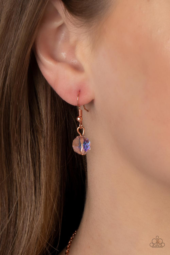 Tasteful Teardrops - Copper Necklace - Paparazzi Accessories - An iridescent peach crystal-like bead twinkles from the top of two mismatched shiny copper teardrop frames at the bottom of an extended shiny copper chain, resulting in a tasteful and timeless pendant. Features an adjustable clasp closure. Due to its prismatic palette, color may vary. Sold as one individual necklace.