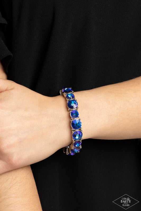 Born to Bedazzle - Blue Oil Spill Bracelet - Paparazzi Accessories - An assortment of oversized blue oil spill rhinestones are pressed into silver frames and threaded along stretchy bands, creating a blinding sparkle around the wrist. Sold as one individual bracelet.
