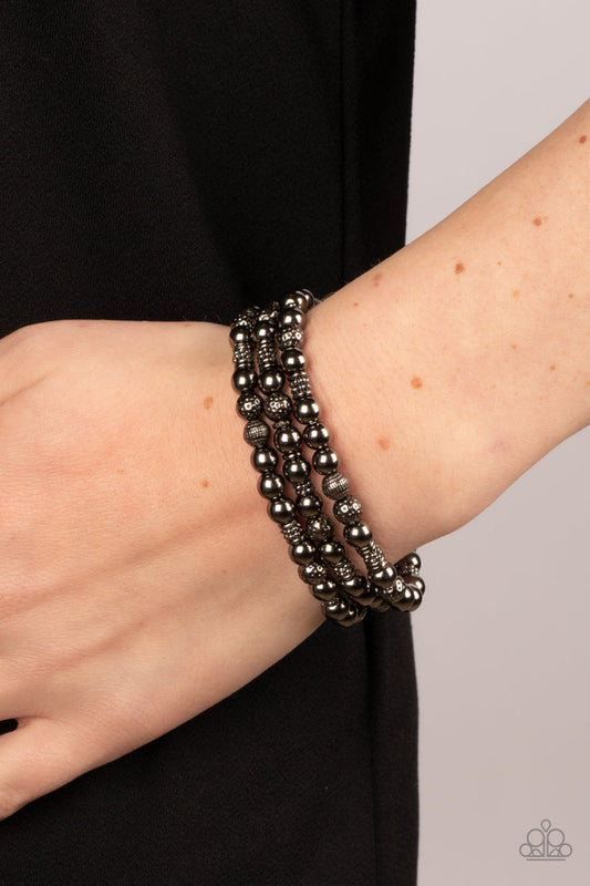 Boundless Boundaries - Gunmetal Black Bracelet - Paparazzi Accessories - A gritty collection of smooth, studded, and textured gunmetal beads are threaded along stretchy bands around the wrist, creating dainty layers. Sold as one set of three bracelets.