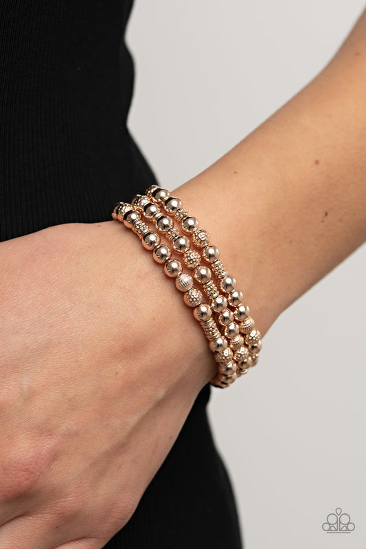 Boundless Boundaries - Rose Gold Stretchy Bracelet - Paparazzi Accessories - A shiny collection of smooth, studded, and textured rose gold beads are threaded along stretchy bands around the wrist, creating dainty layers. Sold as one set of three bracelets.