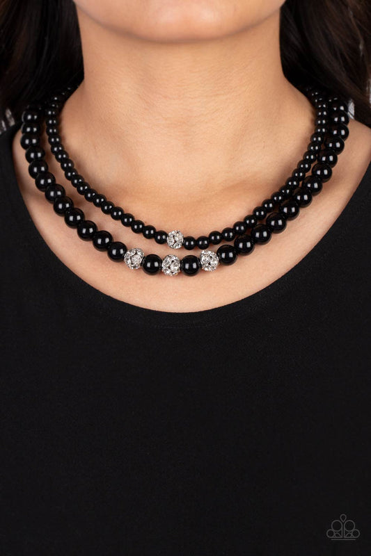 Brilliant Ballerina - Black Necklace - Paparazzi Accessories - Two strands of classic black beads in varying sizes coalesce around the collar in a refined fashion. Silver beads, encrusted in white rhinestones, introduce shimmery detail to each layer, adding a playful spark of shimmer to the timeless design.