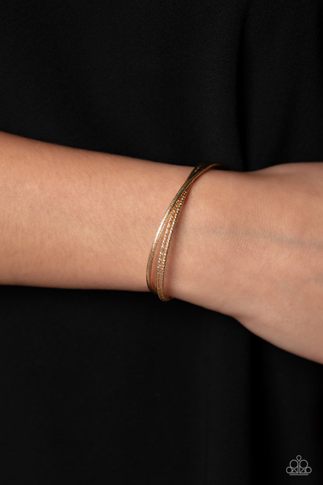 Coachella Curls - Gold Cuff Bracelet - Paparazzi Accessories - One strand of glittery gold and one double strand of textured gold crisscross across the wrist, coalescing into a versatile cuff around the wrist. Sold as one individual bracelet.