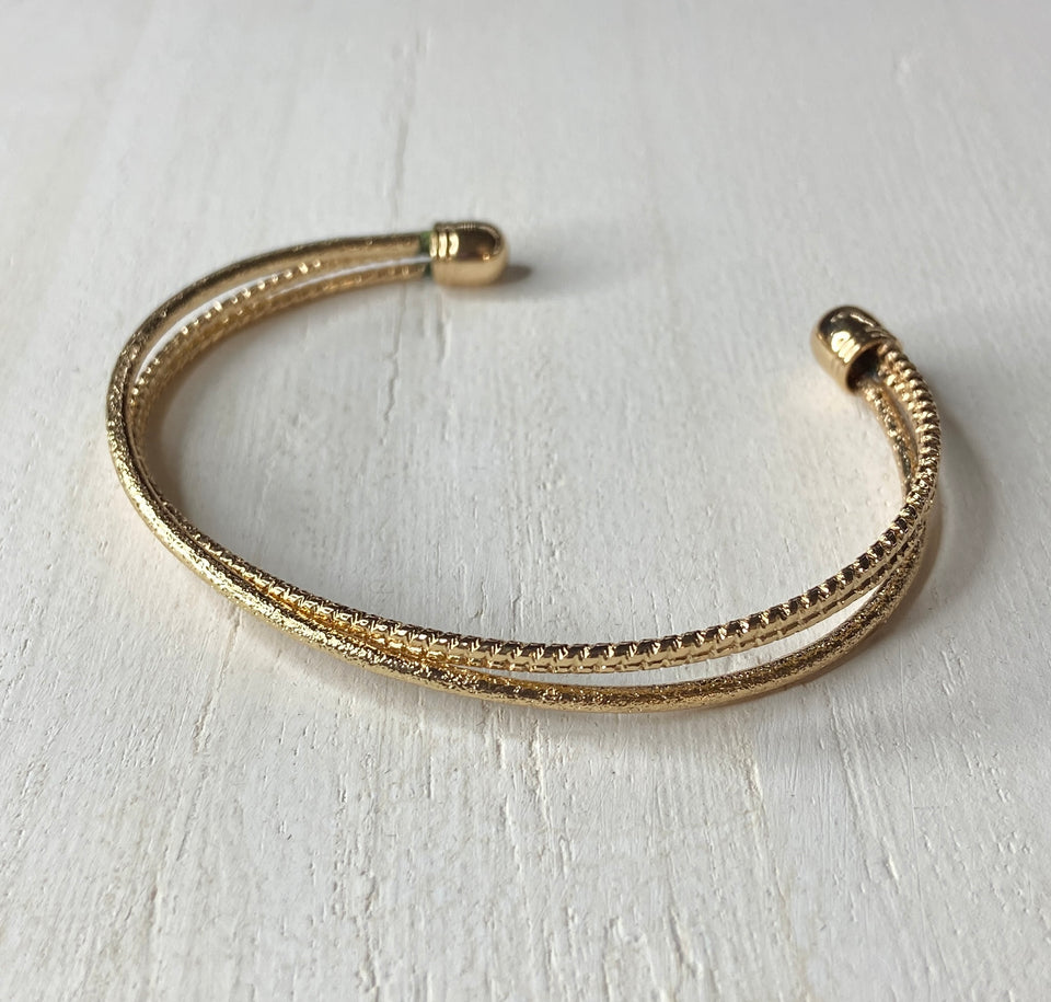 Coachella Curls - Gold Cuff Bracelet - Paparazzi Accessories - One strand of glittery gold and one double strand of textured gold crisscross across the wrist, coalescing into a versatile cuff around the wrist. Sold as one individual bracelet.