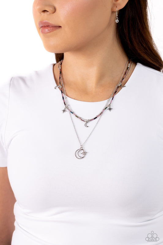 Constant as the Stars - Purple and Silver Necklace - Paparazzi Accessories - Three delicate chains across the chest, for a radiantly layered style. Purple and oil spill glass beads, a cosmic collection of silver stars and crescent moon charms dot the uppermost chain. The centermost chain is accented with dainty silver studs, an oversized silver crescent moon embellished with a sparkling three-dimensional silver star creates a heavenly pendant at the bottom of the longest chain in a radiant finish. 