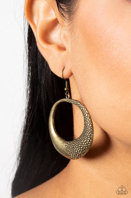 Downtown-  Jungle Brass Earrings - Paparazzi Accessories - One side of an asymmetrical brass hoop is embossed in rugged pebble like texture, culminating in a wildly abstract frame.