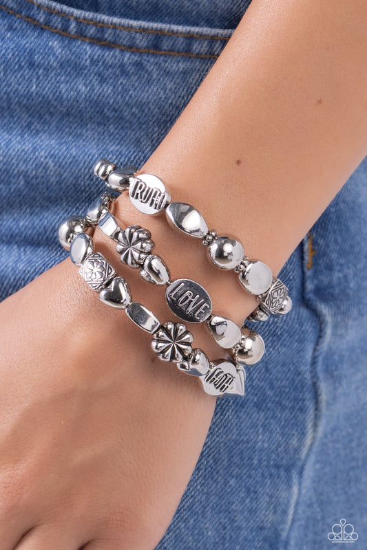 Enchanting Emotion - Silver Infinity Bracelet - Paparazzi Accessories - An enchanting assortment of shiny silver, faceted, and floral embossed beads alternate along a coiled wire, creating a whimsical infinity-style bracelet around the wrist. Additional oval silver beads featuring the words "FAITH," "HOPE," "TRUTH," and "LOVE" finish off the design with an inspirational finish.