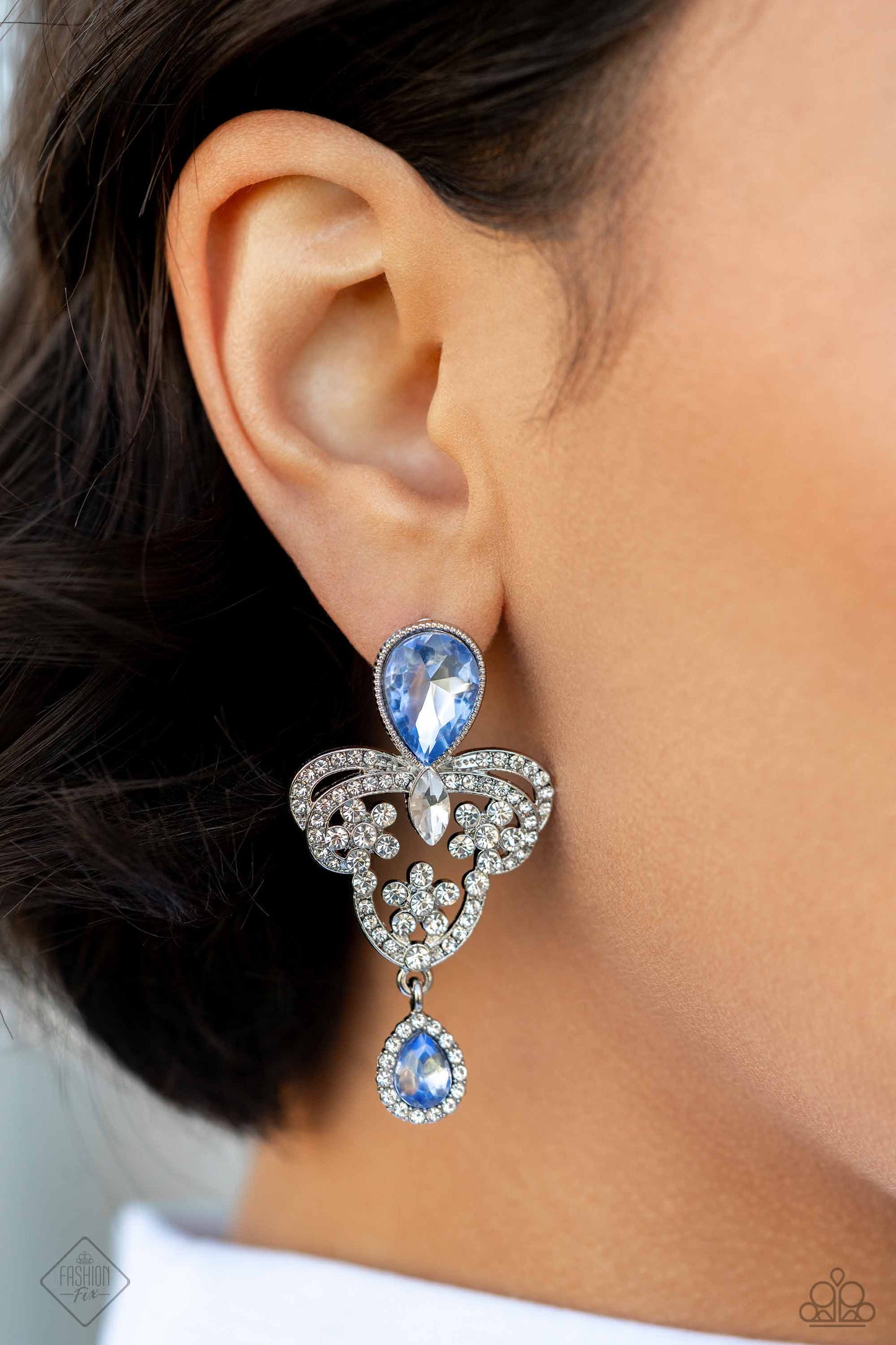Giving Glam - Blue and Silver Earrings - Paparazzi Accessories - Pressed in a silver textured frame, an upside-down blue teardrop gem gives way to a silver, decorative, chandelier-like frame. The decorative frame swirls with dainty white rhinestones and white marquise-cut gems for a timelessly over-the-top sparkle. Bordered by glassy white rhinestones, an upright, smaller blue teardrop gem creates a dainty fringe at the bottom of the frame for an additional pop of elegant color.