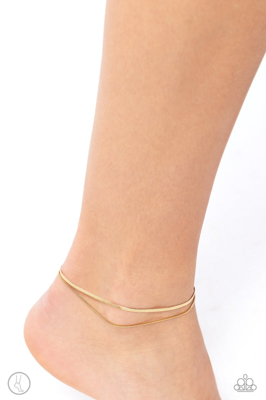 Glistening Gauge - Gold Chain Anklet - Paparazzi Accessories - A strand of flat gold snake chain collides with a dainty square box chain to create an abstract monochromatic display. Features an adjustable clasp closure. Sold as one individual anklet.