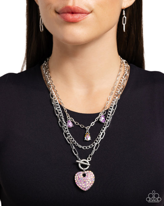 HEART History - Purple Necklace - Paparazzi Accessories - Three mismatched silver chains layer and loop around the neckline. Two purple and an iridescent teardrop gem in silver-pronged fittings dangle from the uppermost chain while a lavender iridescent-rhinestone encrusted heart pendant loops through the lowermost chain for a radiantly, romantic statement.