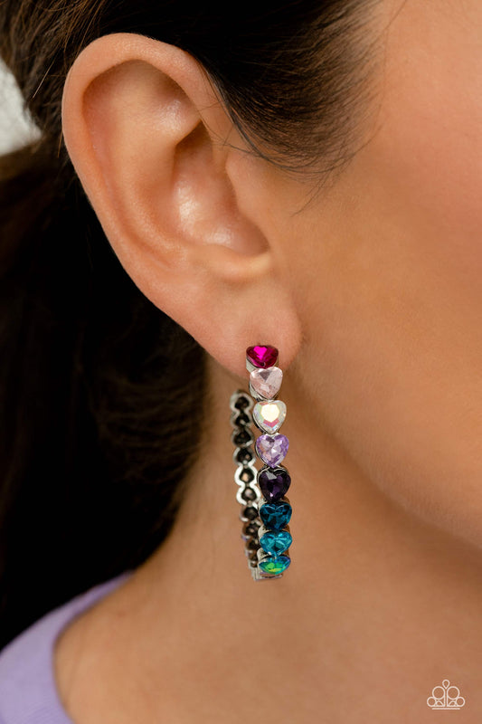 Hypnotic Heart Attack - Multi Heart Hoop Earrings - Paparazzi Accessories - Featuring a scalloped heart frame, glittery heart rhinestones in shades of pink, iridescence, purple, blue, and a refracted green shimmer slowly decrease in size as they curve down the ear to meet dainty silver hearts for a romantic statement. Earring attaches to a standard post fitting. Hoop measures approximately 1 3/4" in diameter.