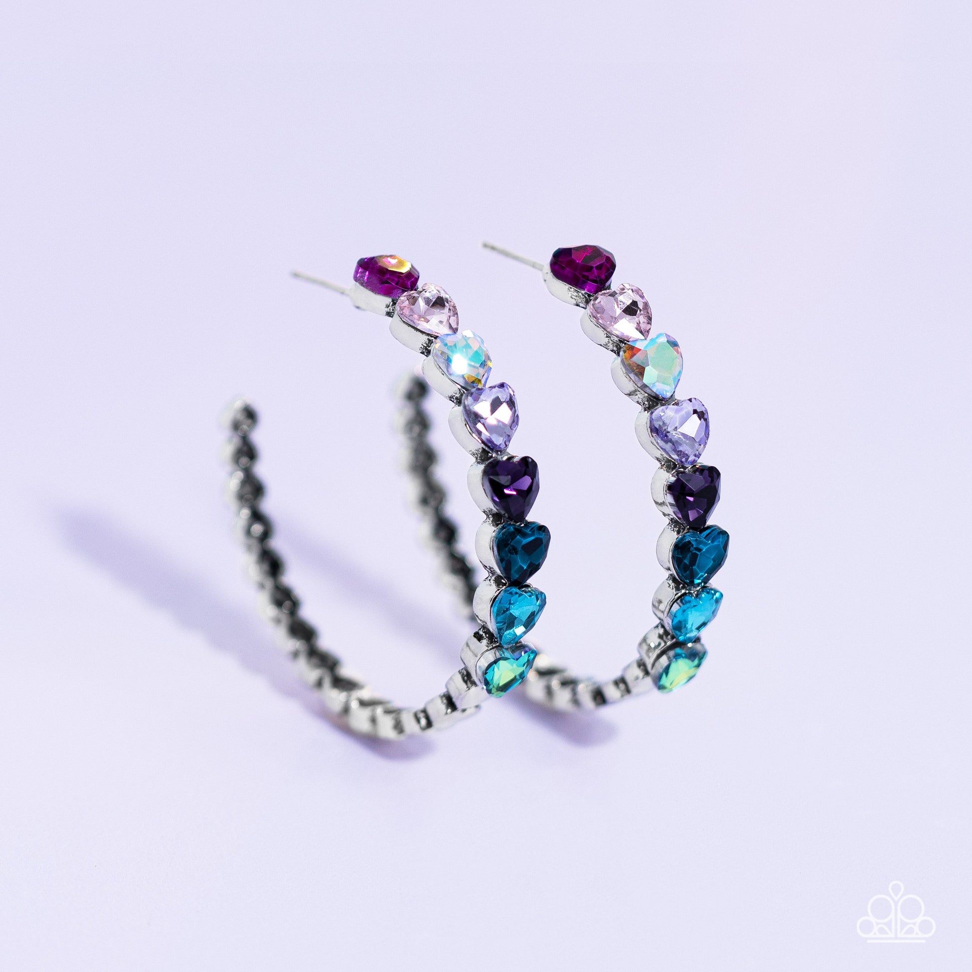 Hypnotic Heart Attack - Multi Heart Hoop Earrings - Paparazzi Accessories - Featuring a scalloped heart frame, glittery heart rhinestones in shades of pink, iridescence, purple, blue, and a refracted green shimmer slowly decrease in size as they curve down the ear to meet dainty silver hearts for a romantic statement. Earring attaches to a standard post fitting. Hoop measures approximately 1 3/4" in diameter.