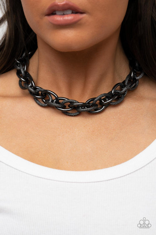 License to Chill - Gunmetal Black Necklace - Paparazzi Accessories - Featuring smooth and glitzy textured finishes, two oversized gunmetal chains interlock into a single chain below the collar for an intense industrial display.