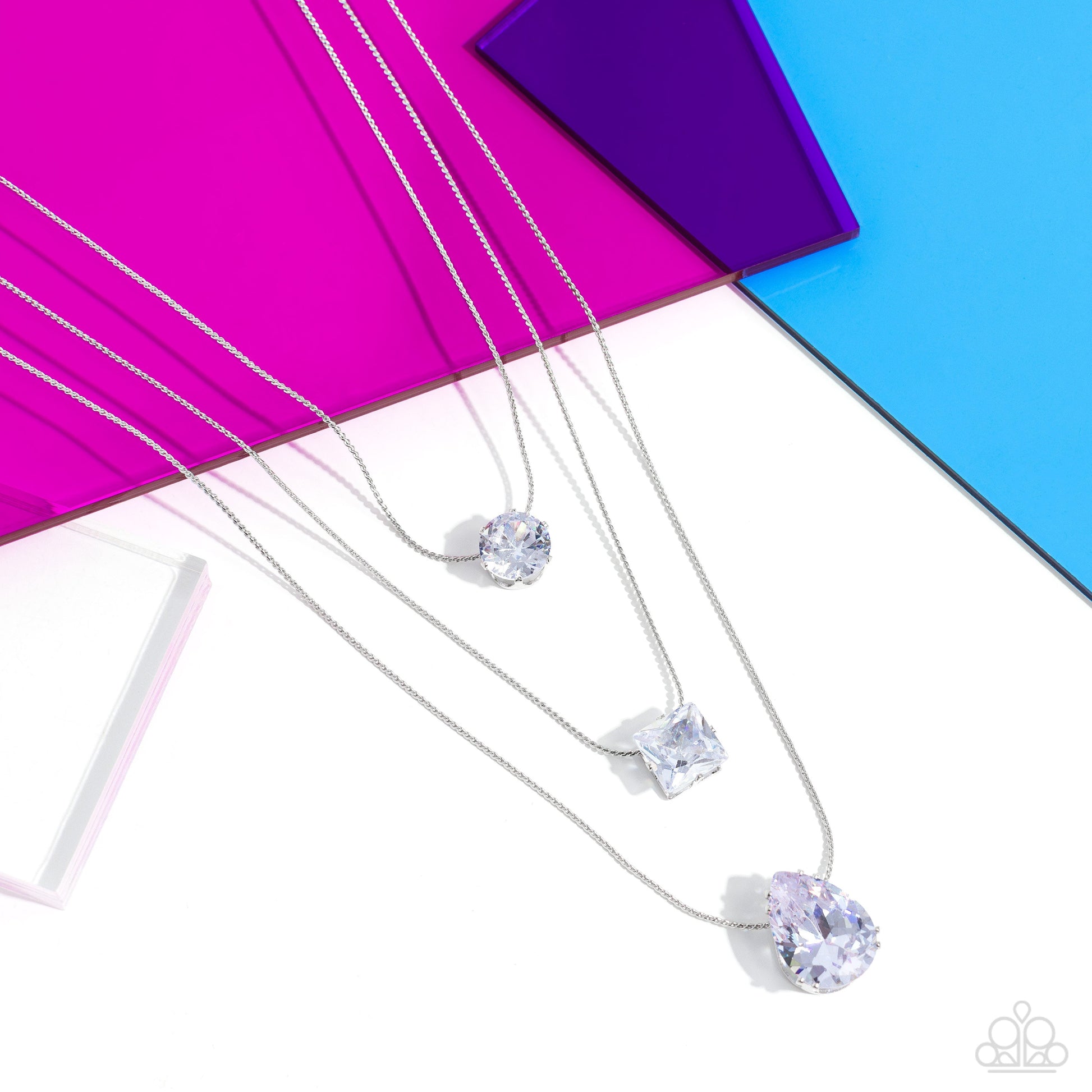 Lustrous Layers - White and Silver Necklace - Paparazzi Accessories - Featuring a subtle iridescent finish, exaggerated, faceted round, square, and teardrop gems layer down the chest from three sleek silver dainty chains, in a refined fashion.