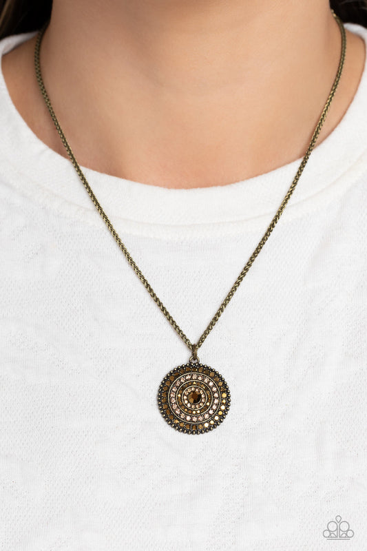 Mandala Masterpiece - Brass Necklace - Paparazzi Accessories - Featured on a scalloped brass pendant, rows of aurum and light colored topaz encircle an aurum rhinestone center, creating an eclectic mandala-like design.