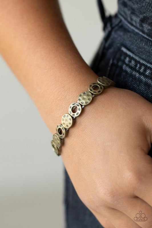 Metro Metalsmith - Brass Bracelet - Paparazzi Accessories - A rustically hammered collection of brass rings and discs are threaded along stretchy bands around the wrist, creating a dainty metallic centerpiece.