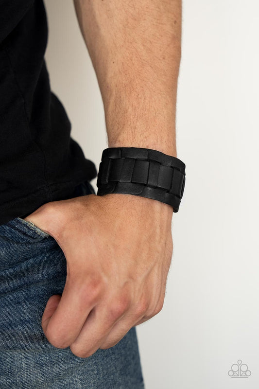 Plainly Plaited - Black Leather Bracelet - Paparazzi Accessories - A black leather band is threaded through the center of interlocking square leather links, creating a plaited pattern around the wrist. Features an adjustable snap closure. 