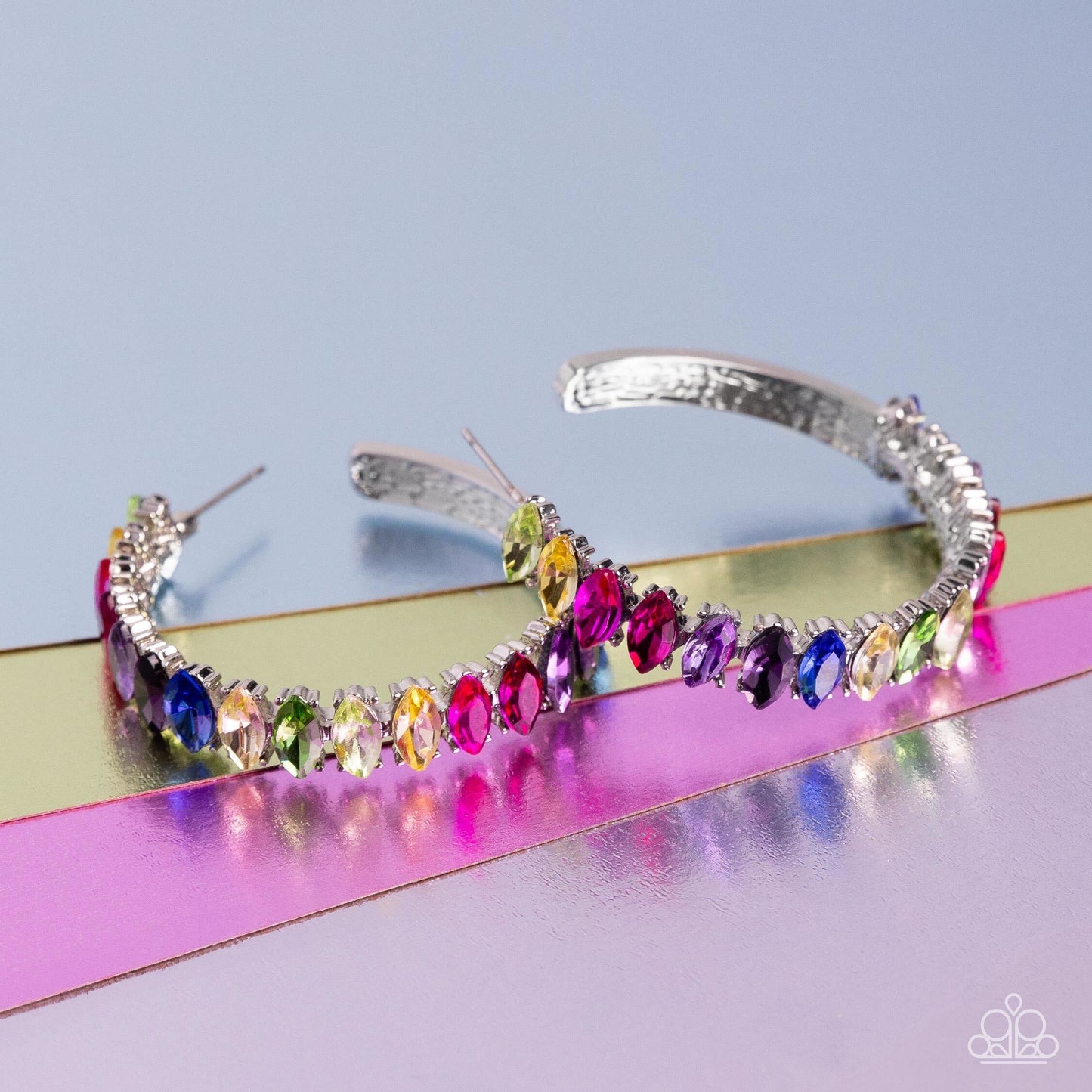 Rainbow Range - Multi Color Hoop Earrings - Paparazzi Accessories - Dazzling colorful marquise-cut gems fall in line along the front edge of a classic silver hoop. The exposed edges create a gritty silhouette, beautifully contrasting with the blinding shimmer of the gems in a stunning finish. Earring attaches to a standard post fitting. Hoop measures approximately 1 1/2" in diameter. Sold as one pair of hoop earrings.