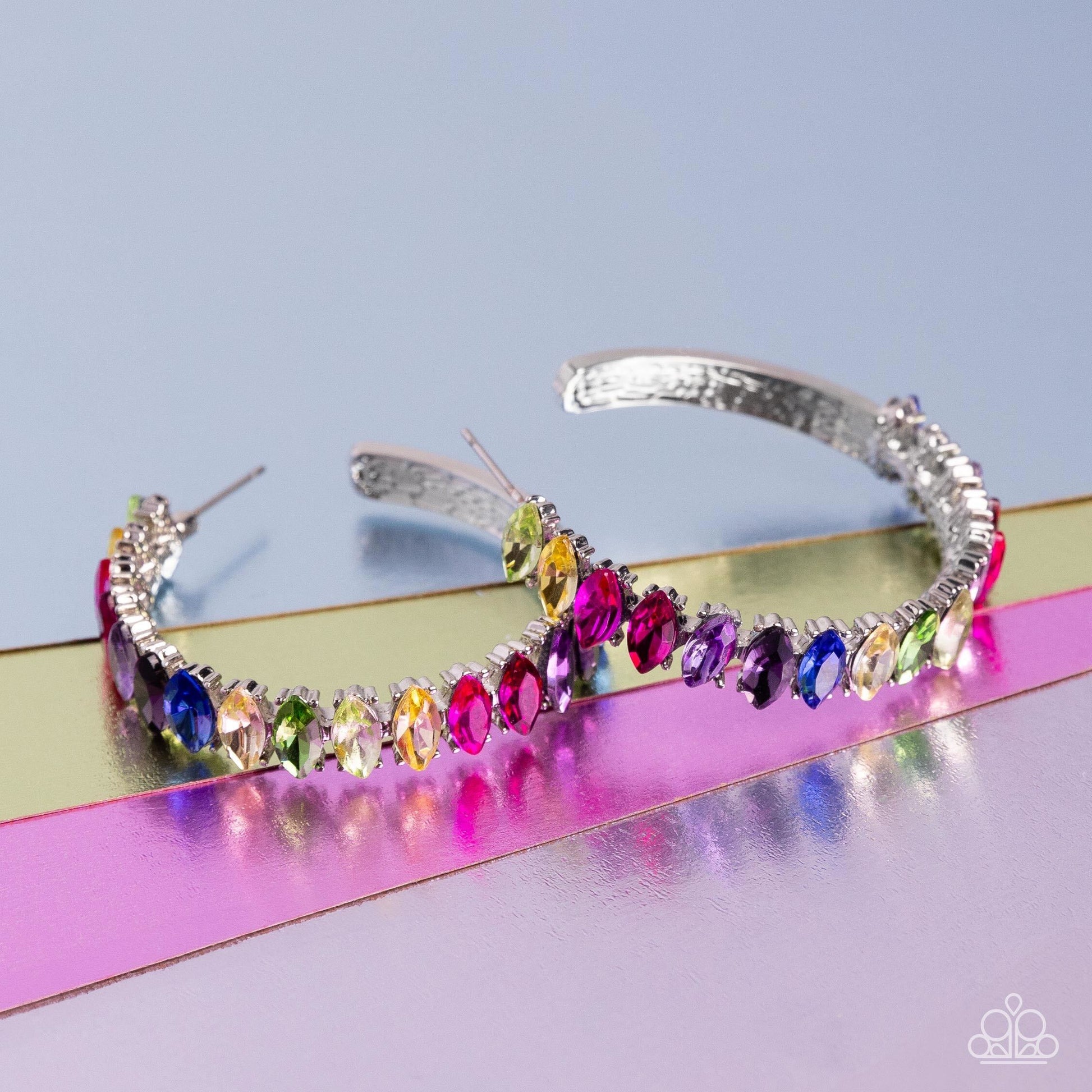 Rainbow Range - Multi Color Hoop Earrings - Paparazzi Accessories - Dazzling colorful marquise-cut gems fall in line along the front edge of a classic silver hoop. The exposed edges create a gritty silhouette, beautifully contrasting with the blinding shimmer of the gems in a stunning finish. Earring attaches to a standard post fitting. Hoop measures approximately 1 1/2" in diameter. Sold as one pair of hoop earrings.