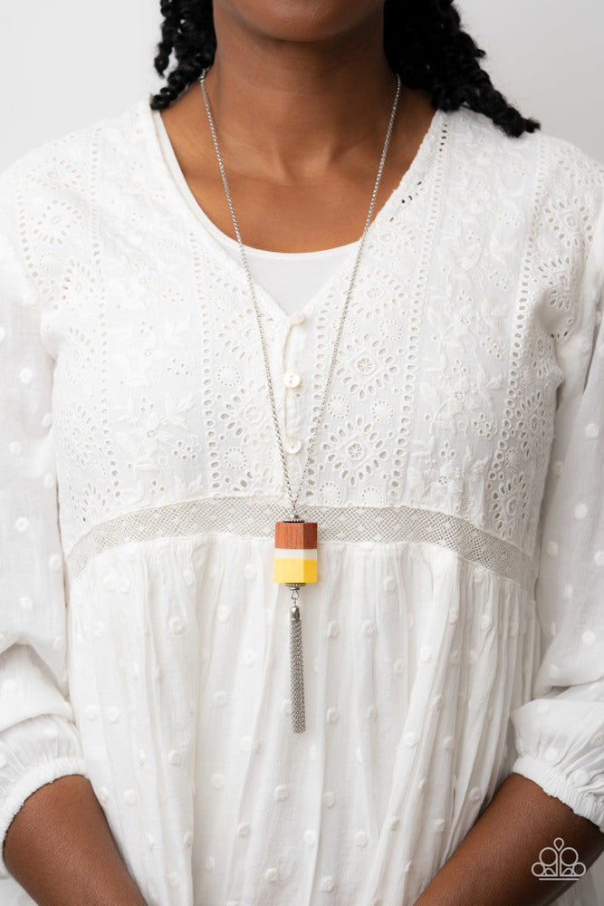 Reel It In - Yellow and Silver Necklace - Paparazzi Accessories - Infused with silver beaded accents, pieces of yellow and brown wood and a white acrylic accent delicately stack into a faceted geometric pendant at the bottom of an extended silver chain. A shimmery silver chain tassel dances from the bottom of the earthy display, adding whimsical movement to the colorful piece.