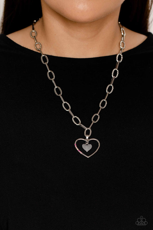 Refulgent Romance - Pink and Silver Heart Necklace - Textured ovals and elongated silver links lead the eye down to an oversized, airy, silver heart frame. Encrusted along one of the curves of the silver heart, dainty rhinestones in shades of pink, including fuchsia, rose, light rose, and iridescence, glimmer for a subtle pop of color. Dangling inside the oversized heart frame, a silver heart pendant swings for a romantic finish.