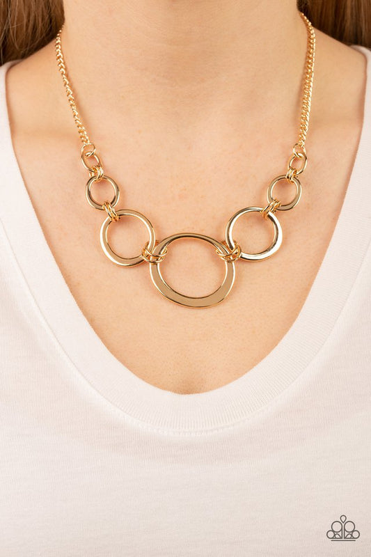 Short Circuit - Gold Necklace - Paparazzi Accessories - An asymmetrical collection of flat gold hoops delicately links with dainty gold rings below the collar. Attached to a classic gold chain, the dizzying rings gradually increase in size for added dimension.