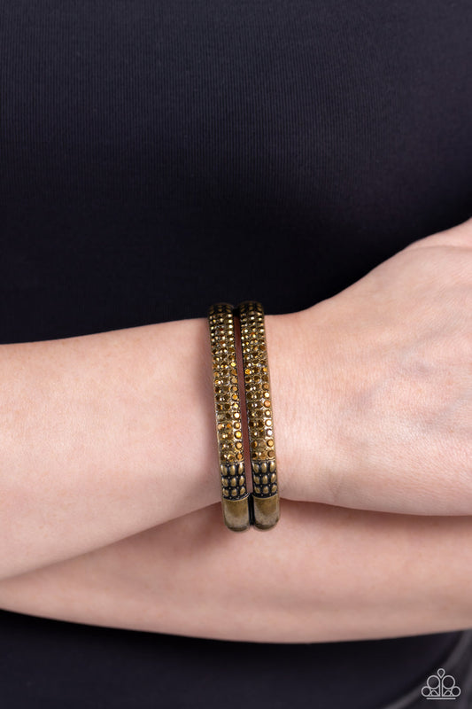 STACKED Up - Brass Bracelet - Paparazzi Accessories - Three rows of dainty aurum rhinestones are encrusted along two thick brass layers as they stack upon the wrist. Rows of studded brass in a dot-motif border the glittery design for additional texture on the industrial showstopper.