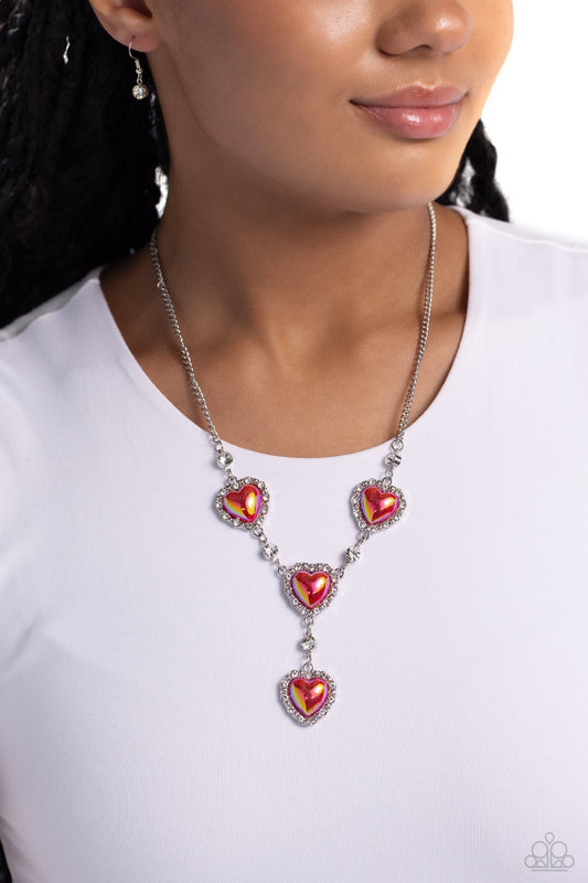 Stuck On You - Red Heart Necklace - Paparazzi Accessories - Pressed in a border of white rhinestones and silver studs, iridescent-brushed red hearts delicately link below the collar in a charming, extended fashion. Solitaire white gems alternate between each heart frame for additional shimmer.