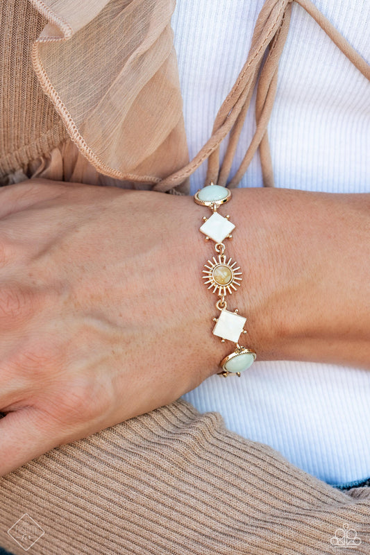 Sunburst Splendor - Gold Bracelet - Paparazzi Accessories - White shells tilted on point, muted blue stones, textured gold circles, and radiating gold sunbursts with multicolored stone centers link around the wrist, creating an earthy display. Each element is wrapped in a gold fitting, magnifying the warm sheen of the design.
