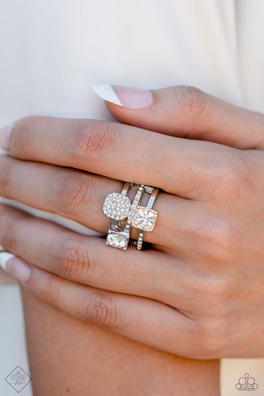 Tailored Two-Tone - Multi Metal (Gold and Silver) Ring - Paparazzi Accessories - Glistening silver bands, infused with dainty white rhinestones, arc across the finger in airy layers. Exaggerated sparkling accents emerge in a haphazard pattern across the bands, including two round-cut gems encased in square fittings and a silver disc covered in tiny white rhinestones. One of the square fittings features a gold finish, establishing an irresistibly glamorous mixed metal palette.