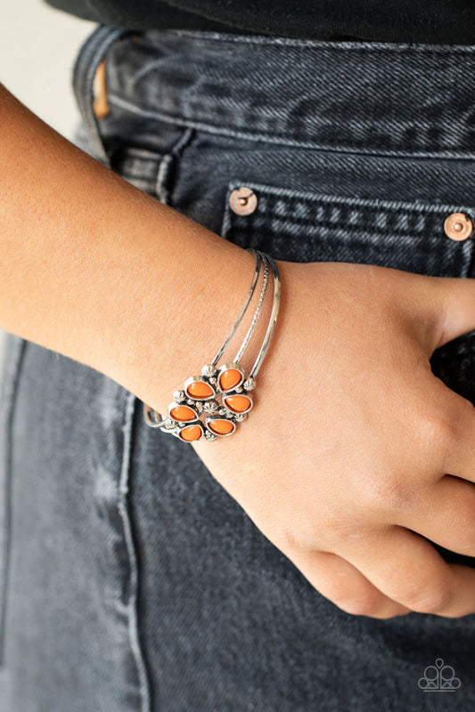 Taj Mahal Meadows - Orange and Silver Bracelet - Paparazzi Accessories - A whimsical collection of glassy orange teardrop beads, dainty silver studs, and silver floral accents coalesce into a colorful centerpiece atop a layered silver cuff.