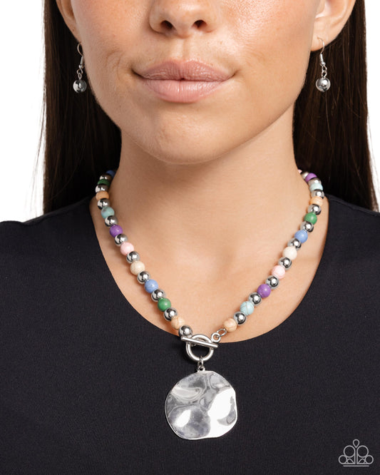 Textured Trinket - Multi Color Necklace - Paparazzi Accessories - Infused along an invisible string, colorful stones alternate with high-sheen silver beads as they connect through a toggle closure. A hammered oversized concaved silver disc cascades from the colorful strand for additional eye-catching detail. Features a toggle closure.