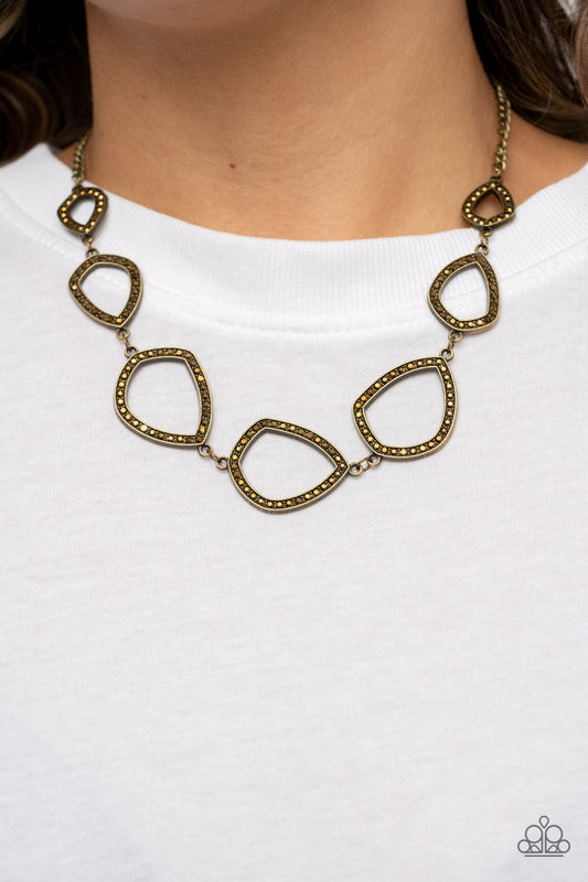 The Real Deal - Brass Necklace - Paparazzi Accessories - Encrusted in glitzy aurum rhinestones, asymmetrical teardrop and geometric brass frames delicately link below the collar for an edgy flair. 