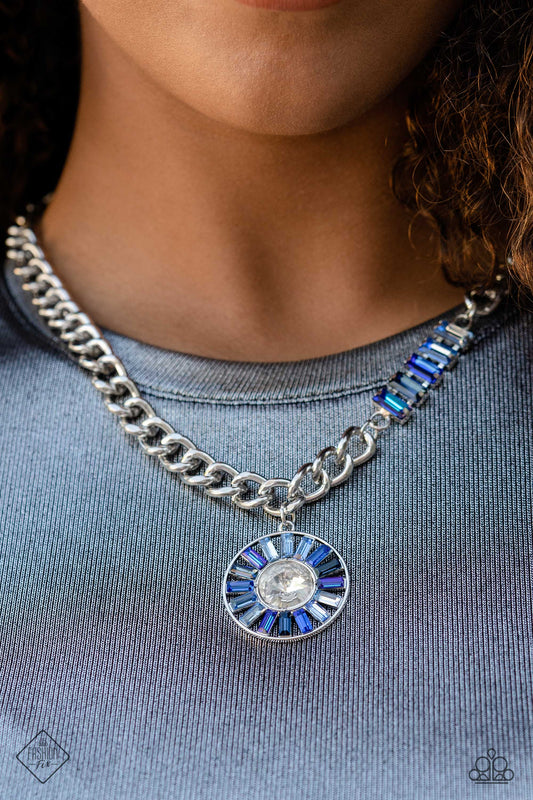 Tiered Talent - Blue and Silver Necklace - Paparazzi Accessories - An exaggerated white gem is encircled by a collection of emerald-cut gems in varying shades of blue, creating a hypnotic pendant that swings from a thick silver curb chain. Five additional emerald-cut gems in the same tranquil spectrum of blue climb one side of the neckline, adding an unexpected splash of color to the bold design.