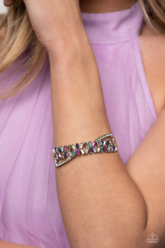 Timeless Trifecta - Multi Color Hinge Closure Bracelet  - Paparazzi Accessories - Modeled after the infinity symbol curves, a row of dainty white rhinestones playfully interacts with emerald-cut gems splashed in shades of amethyst, light blue, pink, smoked topaz, and iridescence. Set in clusters of three, the emerald-cuts haphazardly stack on top of one another for a timeless, geometric radiance atop the wrist.