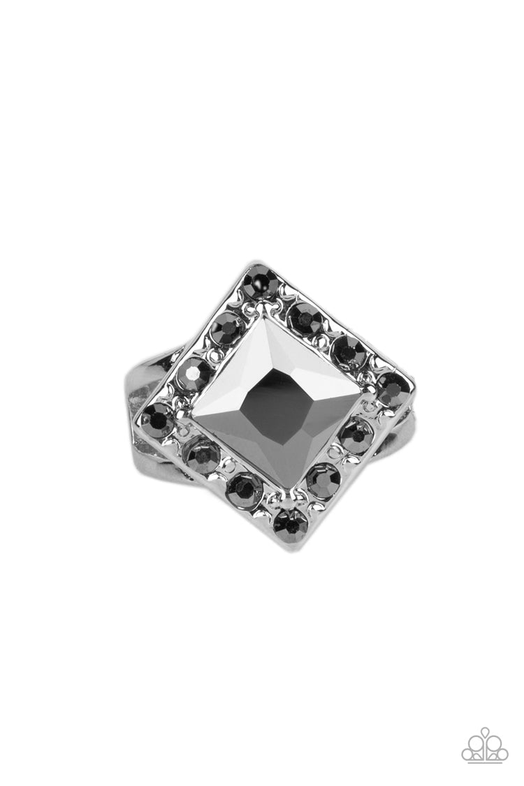 Transformational Twinkle - Silver Ring - Paparazzi Accessories - An oversized, square-cut, hematite rhinestone is tilted on a point and framed by tiny hematite gems. As it sits atop a pair of sleek silver bands, the faceted surface of the centerpiece catches and reflects the light of the accents that surround it, magnifying its impressive impact. Features a dainty stretchy band for a flexible fit. Sold as one individual ring.