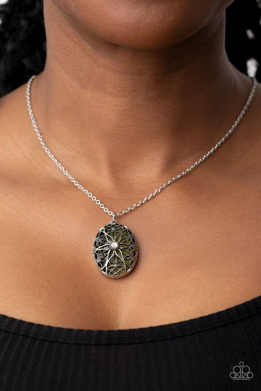 Venice Vacation - Green and Silver Necklace - Paparazzi Accessories - Dotted with a glitzy white rhinestone center, studded and smooth floral filigree detail blooms across the front of an oversized and Olive Branch cat's eye stone, resulting in a whimsical pendant at the bottom of a silver chain.