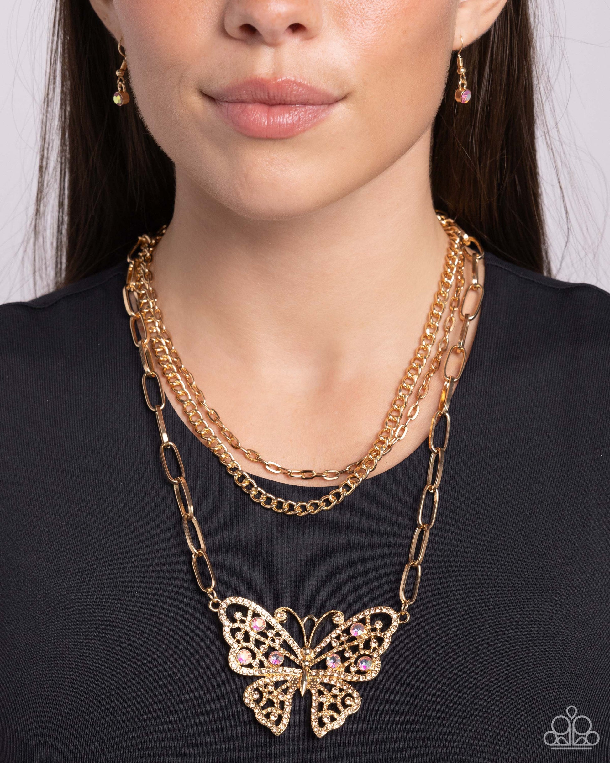 Winged Wonder - Gold Iridescent Butterfly Necklace - Paparazzi Accessories - Three mismatched gold chains interlock and cascade around the neckline in endless layers. A light peach and light peach iridescent-infused gold butterfly flutters at the bottom of the display for a whimsical finish.