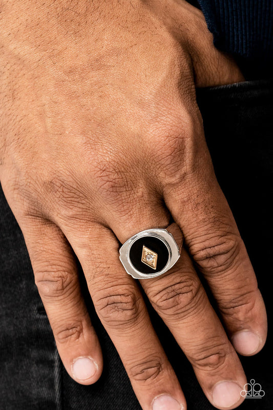 Alumni - Black and Silver Ring - Paparazzi Accessories - A solitaire white rhinestone is pressed into the center of a gold diamond-shaped frame that sits atop a painted black backdrop.