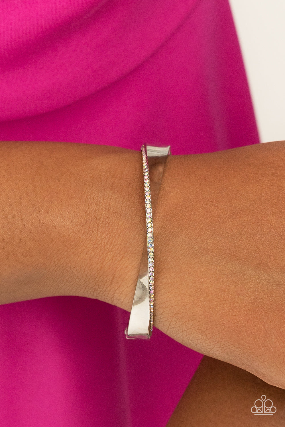 Artistically Adorned - Multi Iridescent - Silver Bracelet - Paparazzi Accessories - An oversized, warped, shiny silver bracelet wraps around the wrist in an artistic manner. A dainty row of iridescent rhinestones encrusts along the curves for an understated, elegant dazzle. Features a hinged closure. Sold as one individual bracelet.