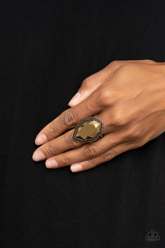 Avant-GRANDEUR - Brass Ring - Paparazzi Accessories - An oversized faceted aurum gem is nestled inside a scalloped brass frame radiating with studded textures, resulting in a radiant centerpiece atop the finger.